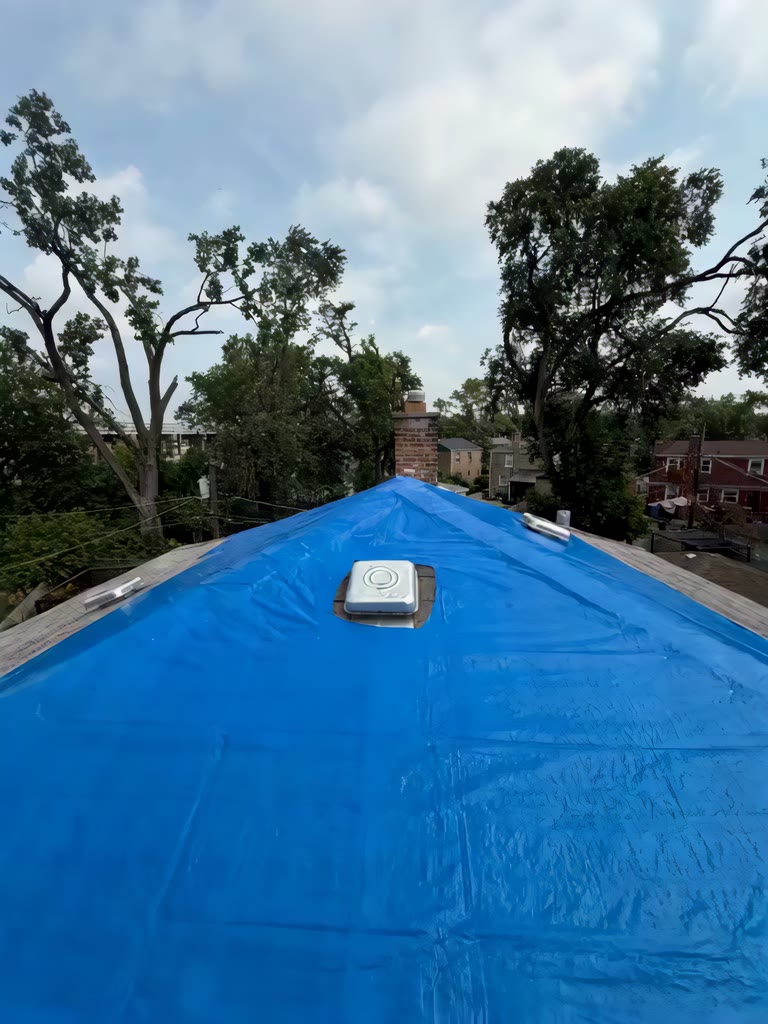 Blue emergency tarp secured over the ridge of a roof